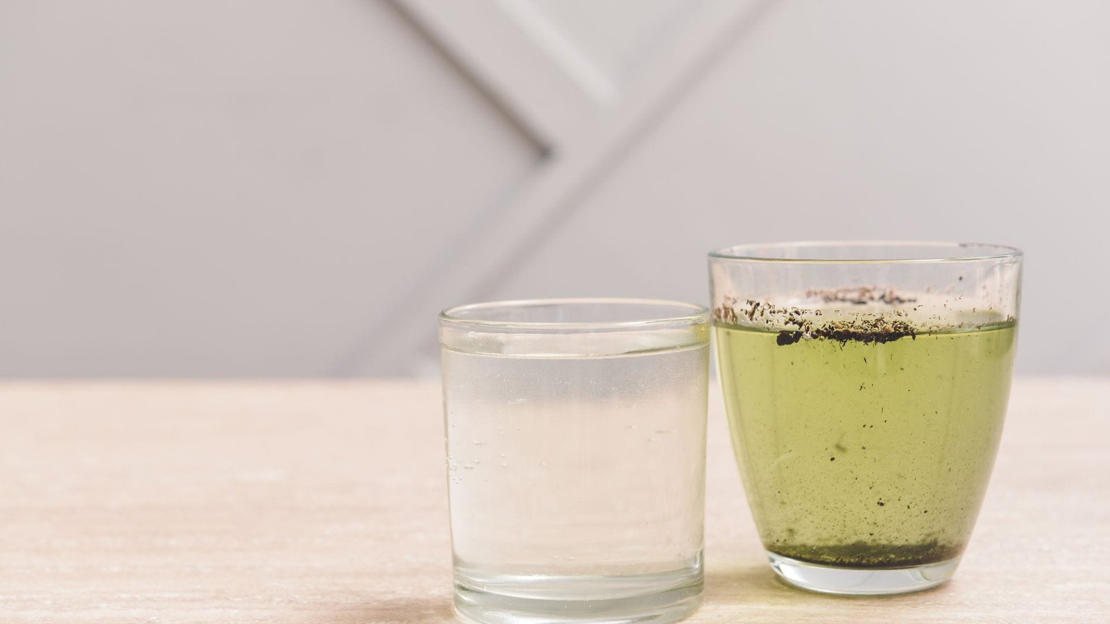 Coliform bacteria well water comparison: clear glass with pure water versus murky glass with sediments.