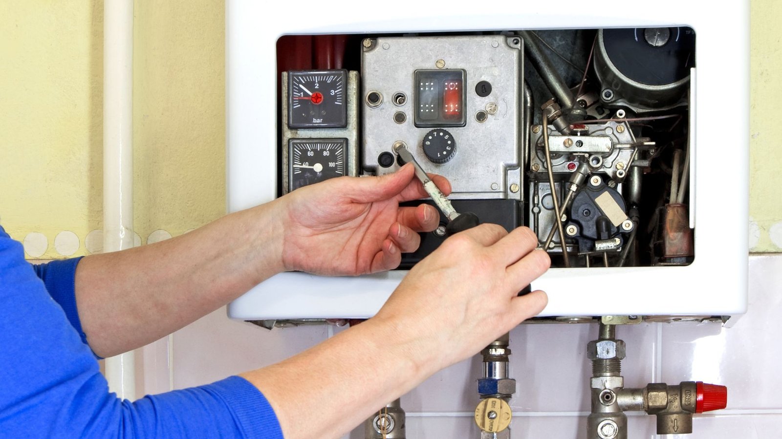 Water heater maintenance closeup: technician adjusts boiler components, showing expertise in system safety and efficiency.