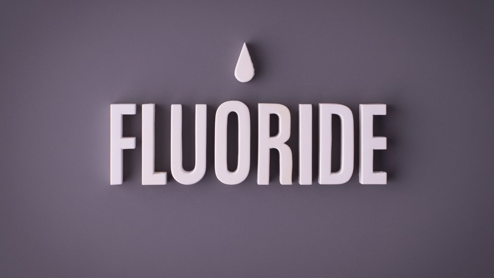 Fluoride minimalist design featuring bold text and water droplet icon on gray background emphasizing water connection.