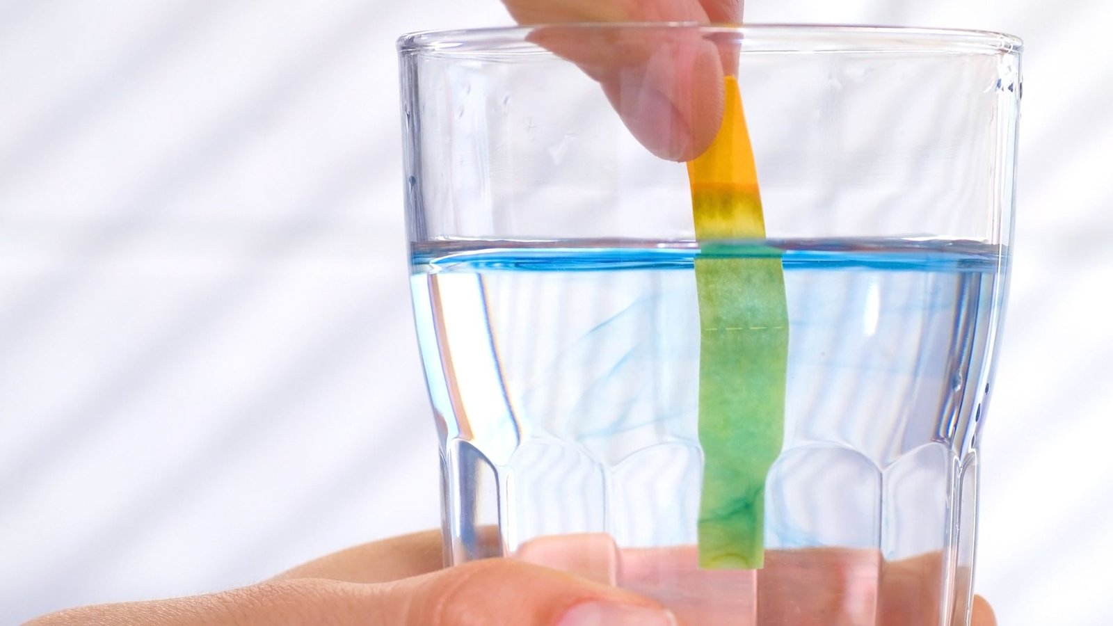 Reverse osmosis water pH test showing blue-tinted liquid with pH strip indicating alkaline level.