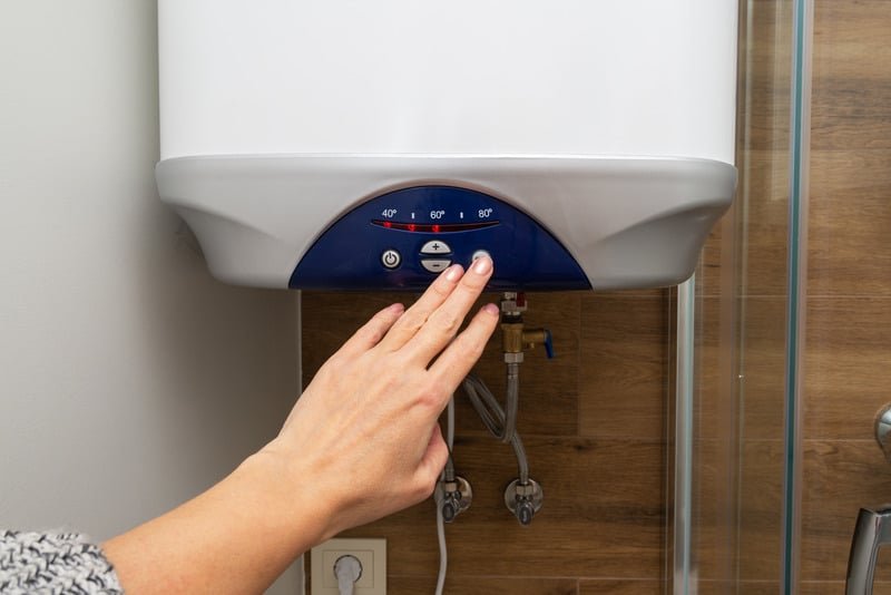 Tankless water heater close-up with control panel and connecting pipes in modern indoor setting.