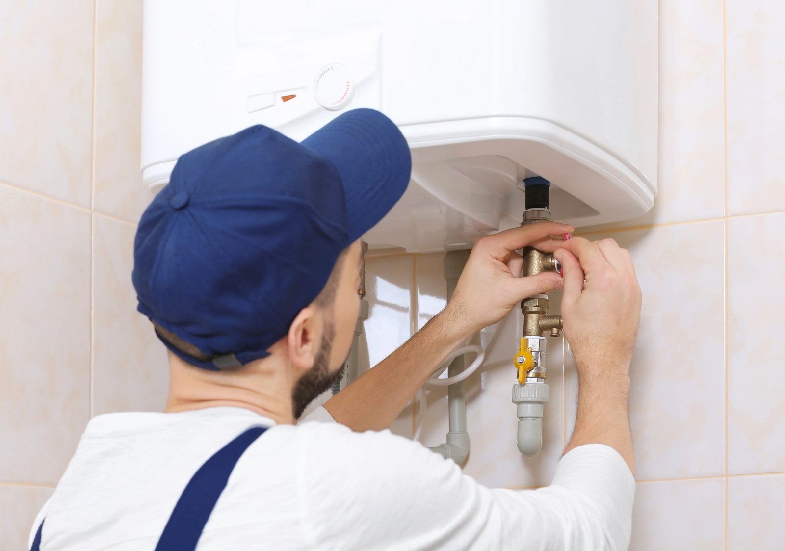 Rheem Water Heater Reviews: Technician performs maintenance on modern water heater in tiled utility room.