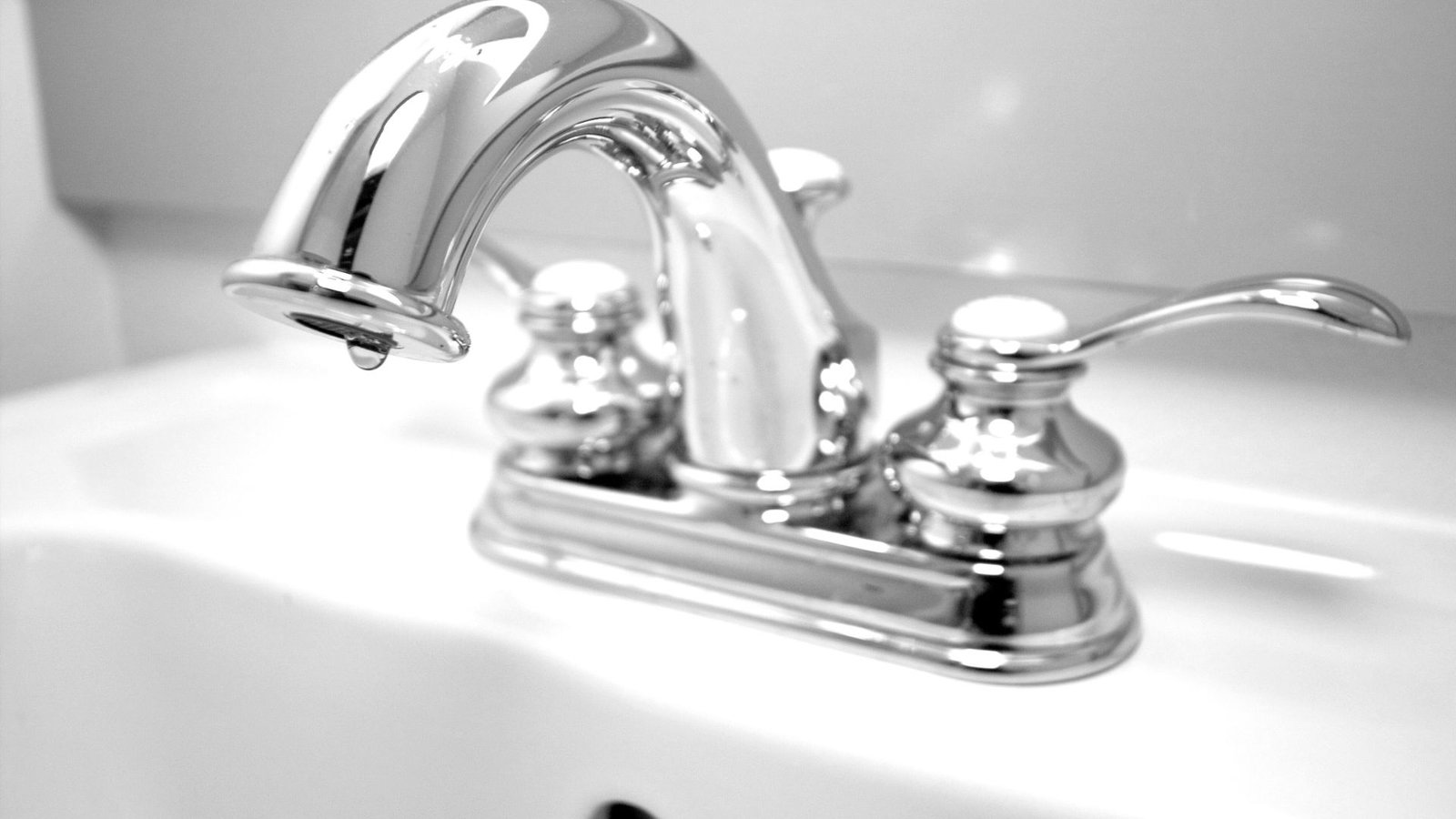 Water Bills Sleek modern chrome faucet with dual handles, arch design, on white ceramic sink.